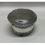 A circular silver ring box on ball and claw feet.