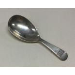 A silver caddy spoon with line decoration to handl