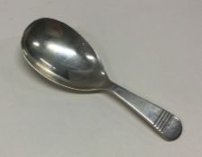 A silver caddy spoon with line decoration to handl