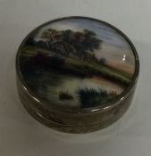A small circular silver and enamelled compact with