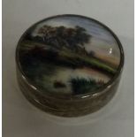 A small circular silver and enamelled compact with