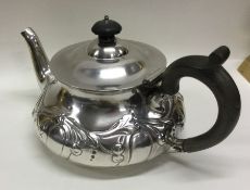 A stylish silver teapot decorated with swirls and