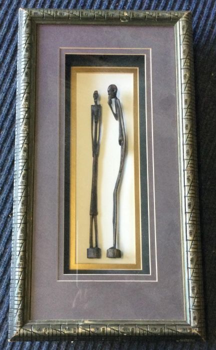 Two wooden tribal figures encased within a framed