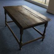 An Antique oak plank top table on stretcher base.