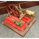 A cast iron steam engine in red on mahogany base.