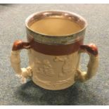 A large pottery three handled mug with silver rim