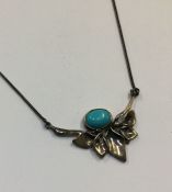 A silver and turquoise necklace with leaf decorati