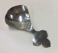 A large silver caddy spoon with leaf decoration. L