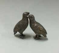 A pair of cast silver birds in seated positions. A