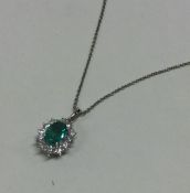An attractive emerald and diamond oval pendant on