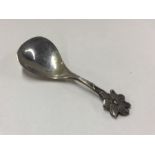 A small silver caddy spoon with floral decoration.