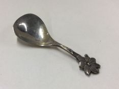 A small silver caddy spoon with floral decoration.