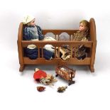 An oak doll's crib containing a peg doll, a pair of early 19th century miniature dolls,