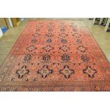 An Afghan carpet, the red ground with repeated medallions within matching bands,