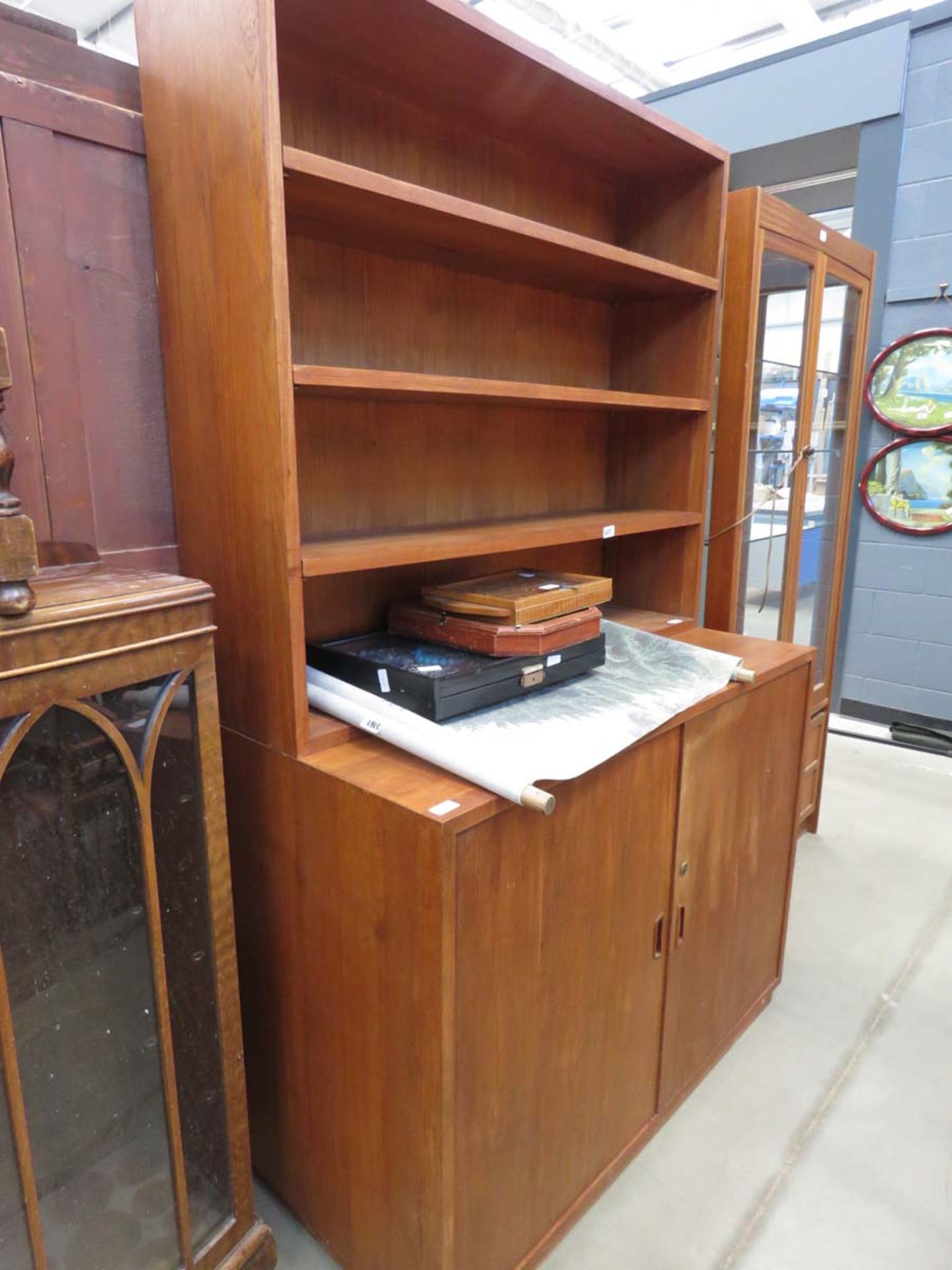 A teak open bookcase with double cupboard space under