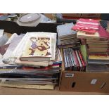 Stack and a box containing vinyl records and CDs and reference books