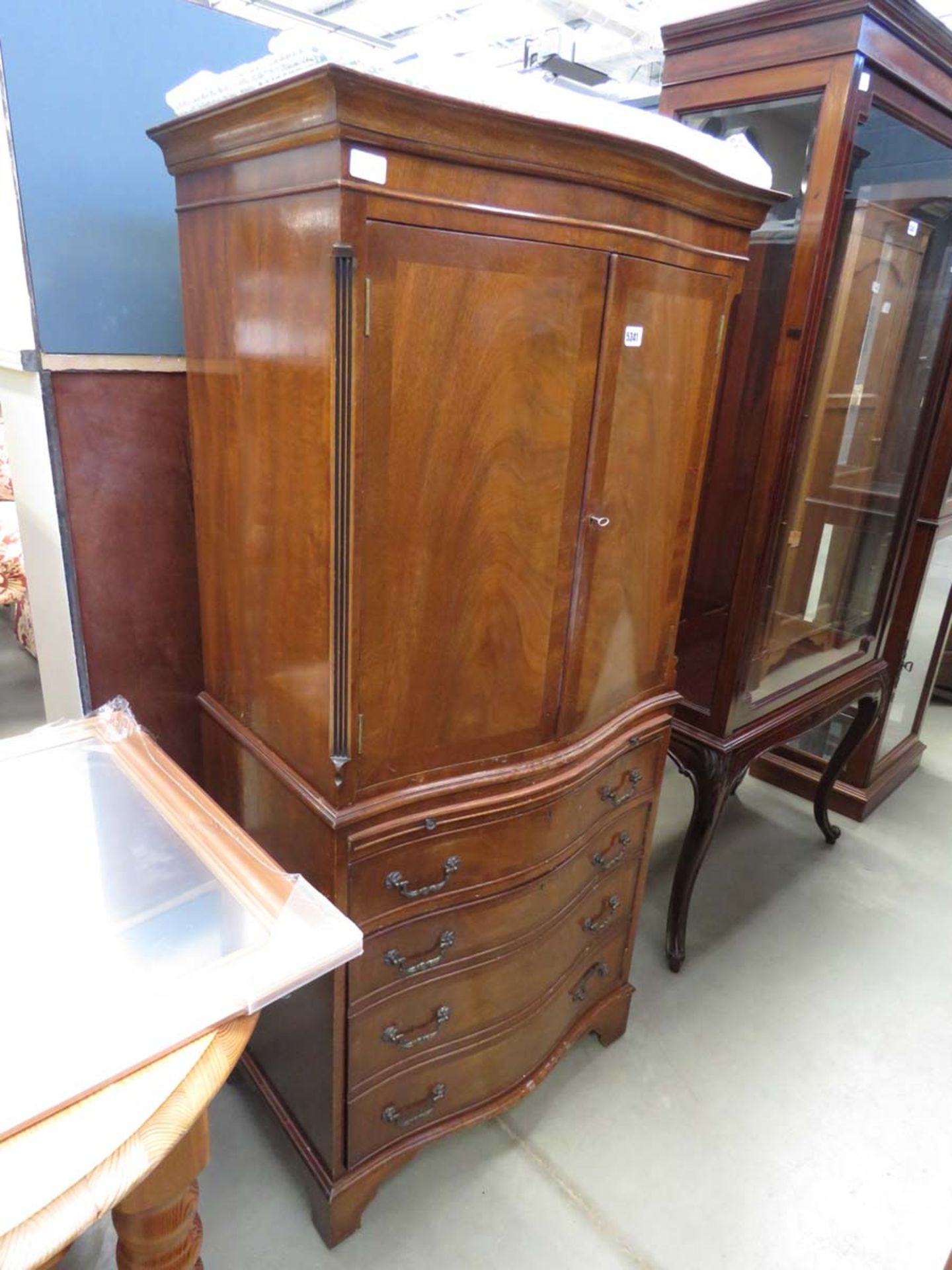 A reproduction mahogany serpentine fronted cabinet with slide and drawers under