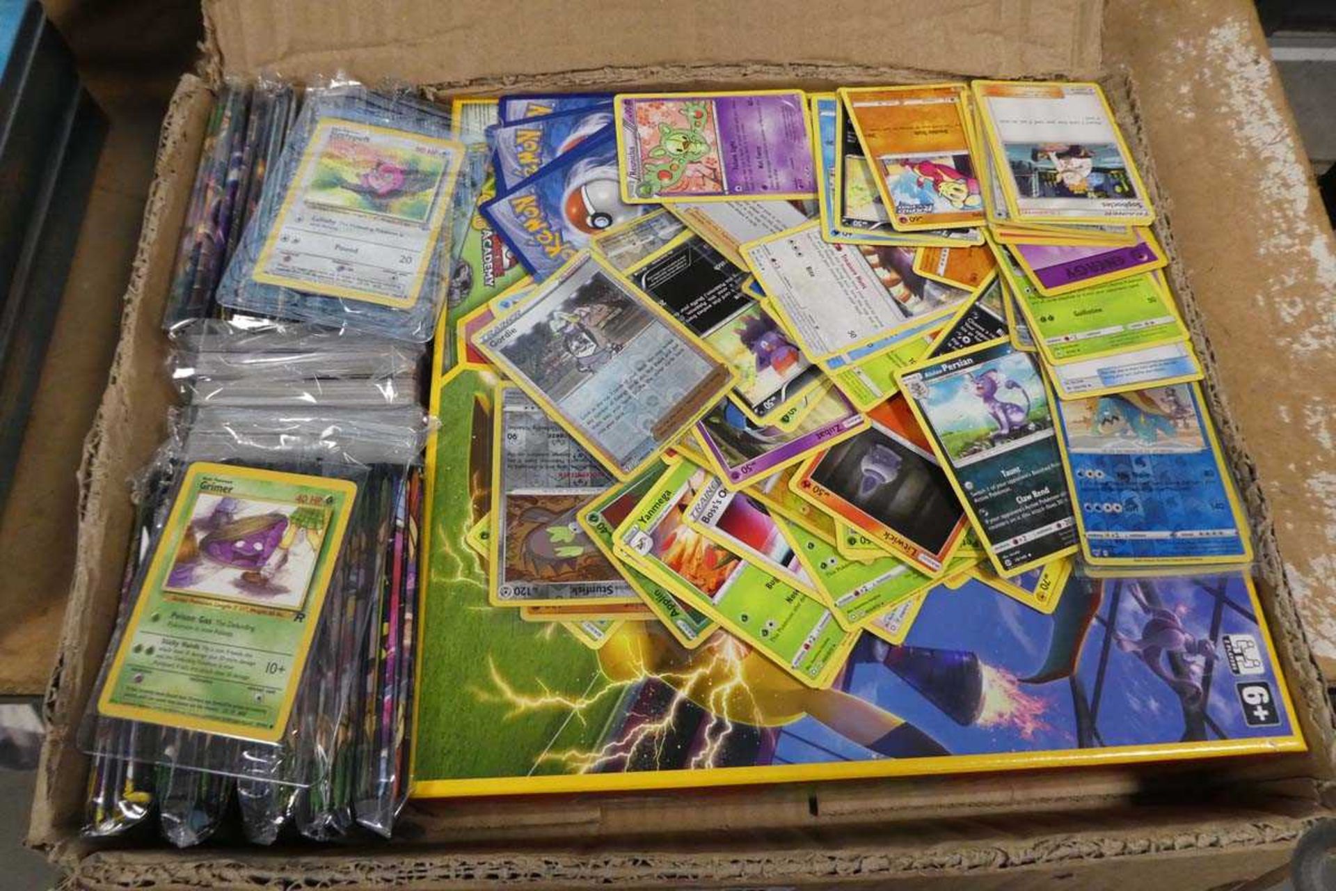 Box containing various Pokemon cards, Pokemon battle academy board and other accessories