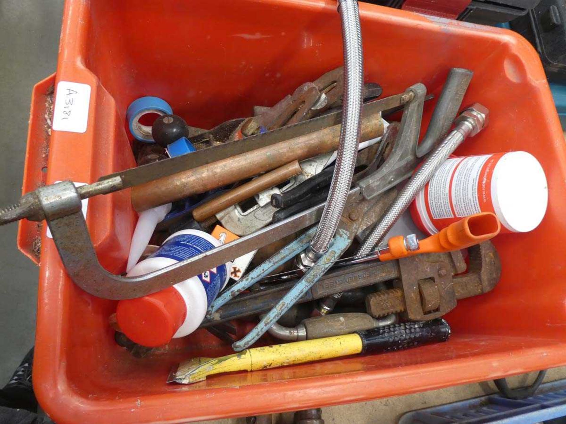 Red plastic tool box containing saws, tin snips, stilsons, scrapers etc