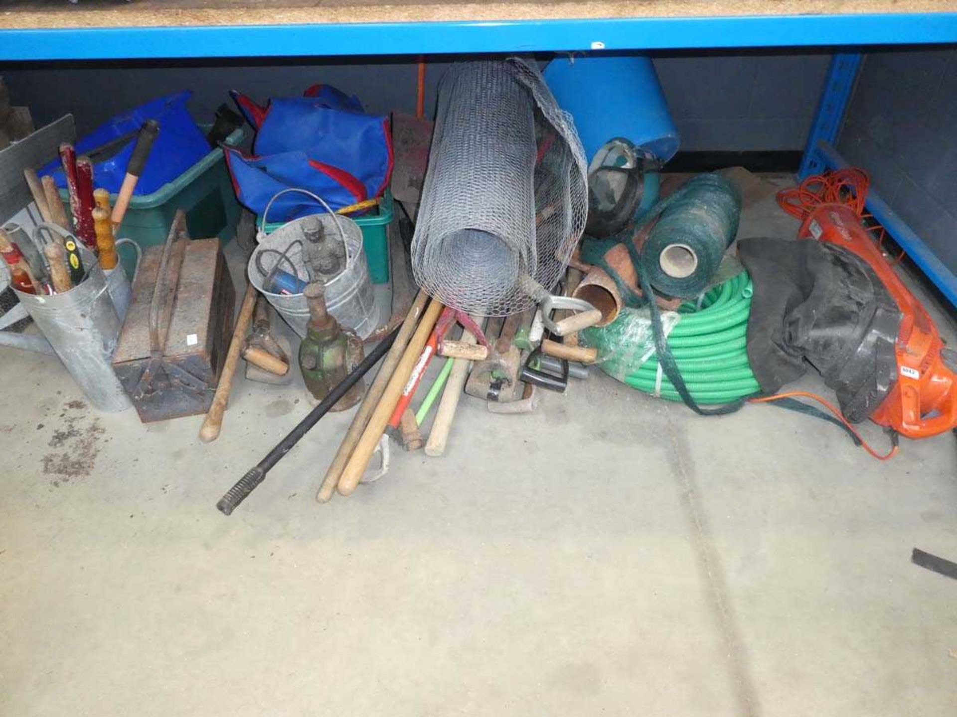 3 quarters of an underbay containing chicken wire, hose, leaf blower, garden tools, jacks, pickaxes,