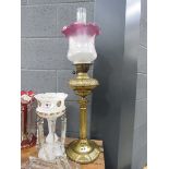 A Corinthian-style oil lamp with brass reservoir and etched clear/pink glass shade, h. 76.5 cm