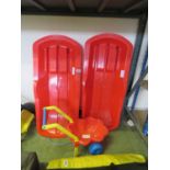 2 red plastic pullalong sleds together with a kids play wheelbarrow