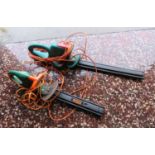 2 green electric powered hedge cutters