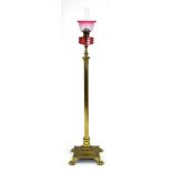 A Victorian brass standard lamp of columnar form surmounted by a cranberry glass reservoir and