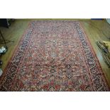 +VAT A Persian carpet with a red ground and foliate motifs, 540 x 329 cm *Please Note: VAT will be