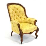 A Victorian walnut and button upholstered fireside armchair on turned front legs with castors