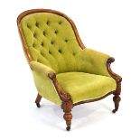 A Victorian oak and button upholstered fireside armchair on turned legs with castors