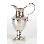 A George III silver cream jug of helmet form with beaded handled on a square plinth foot, London