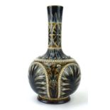 A Doulton Lambeth bottle vase relief decorated with stylised leaves on a beaded blue/treacle ground,
