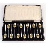 A set of twelve silver, gilt and enamelled teaspoons, decorated in white and black in the Art Deco