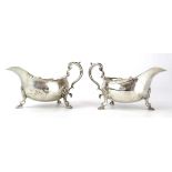 A pair of early 20th century silver sauce boats of typical form with c-scroll handles on hoof