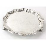 A late 20th century silver salver of circular form with piecrust border on three scrolled feet,