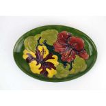 A Moorcroft shallow dish of oval form decorated with hibiscus on a green ground, w. 23 cmCondition