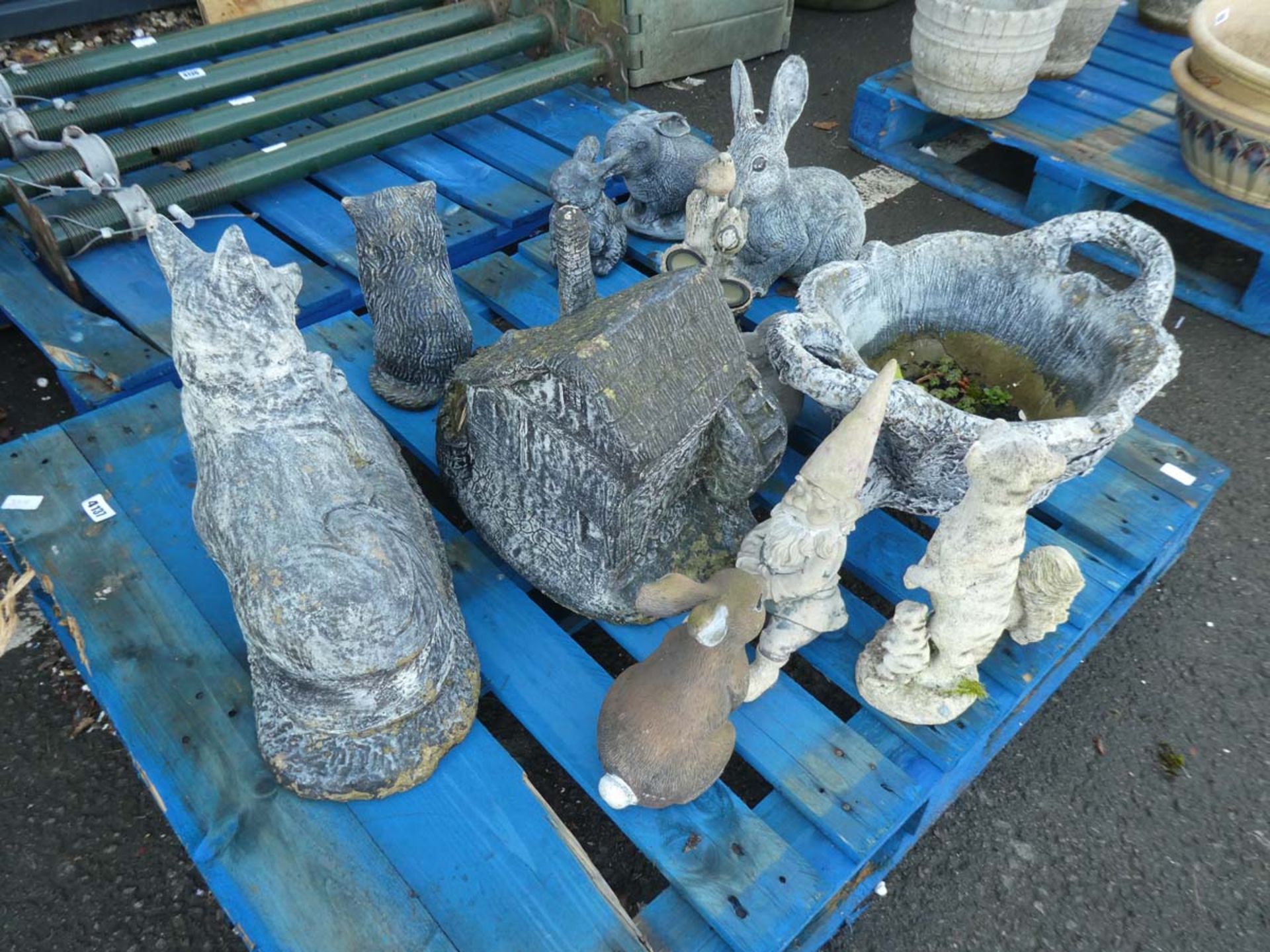 A pallet of garden ornaments including wishing well, concrete dog, concrete rabbits, meerkats etc