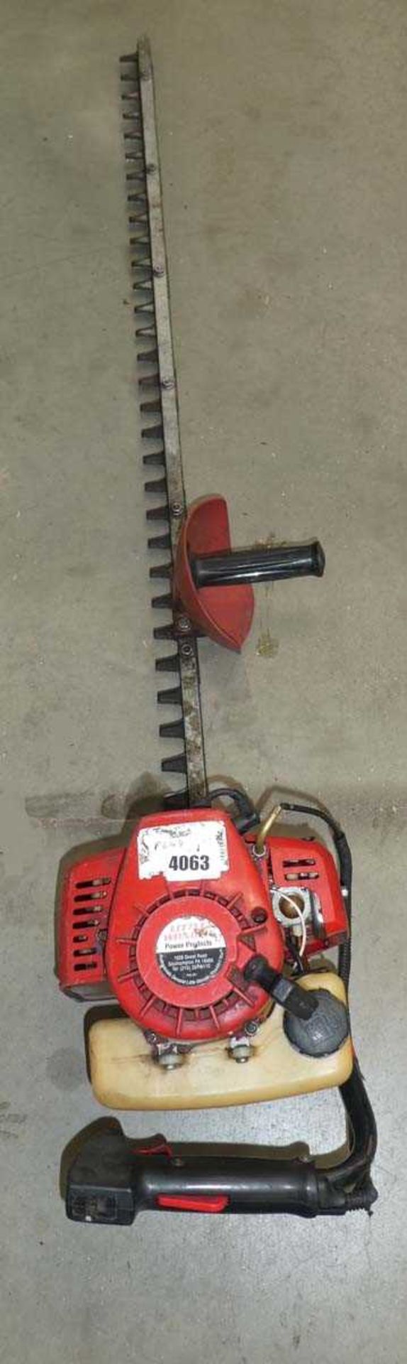 Red petrol powered hedge cutter