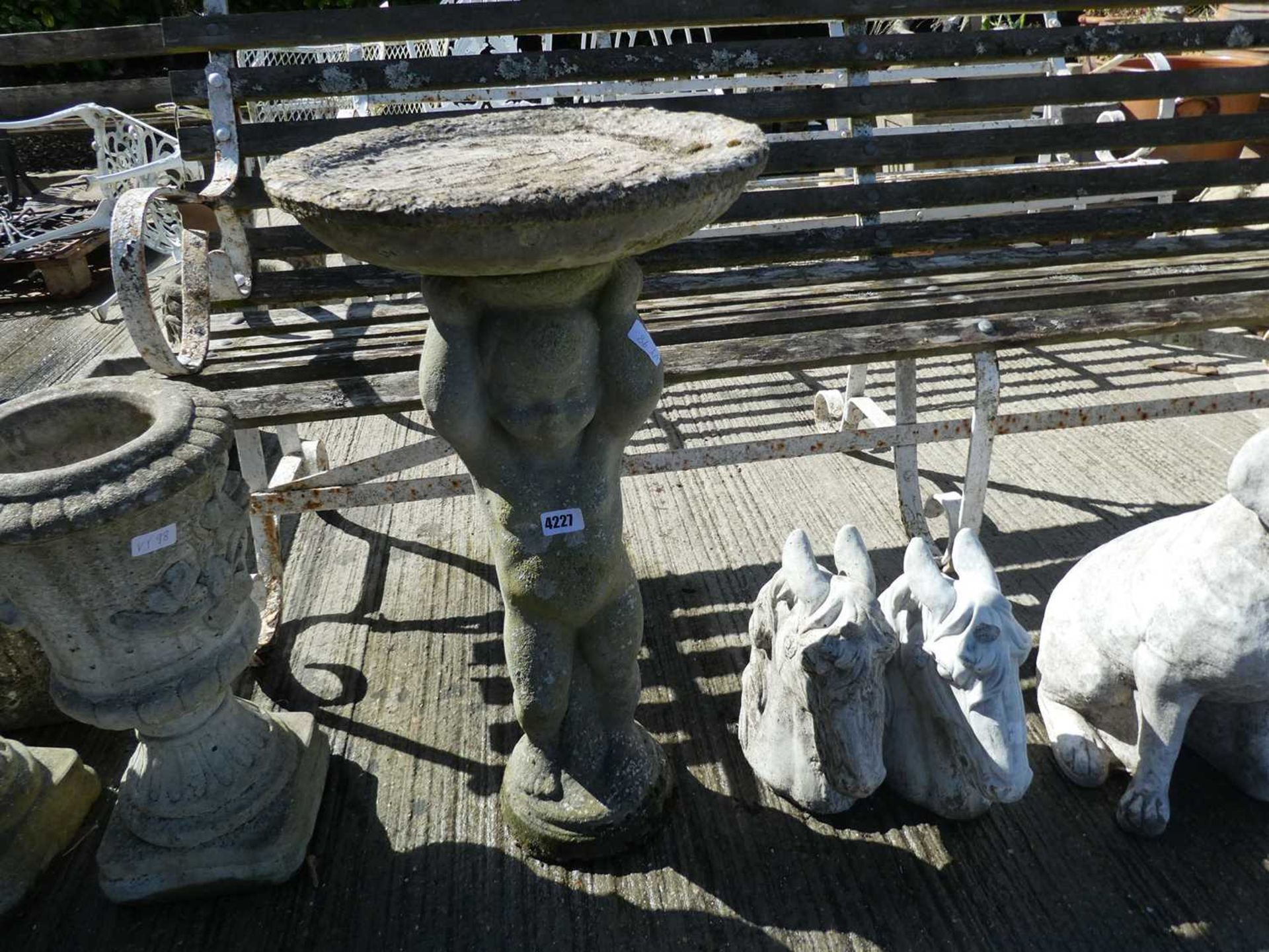 Concrete birdbath in the shape of a cherub holding a tray, including two concrete figures of horse