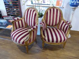Pair of ornate gilt framed open armchairs with red and beige striped upholstered seats, backs and