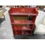 Red painted open front wooden bookcase with plied gilt and floral decoration