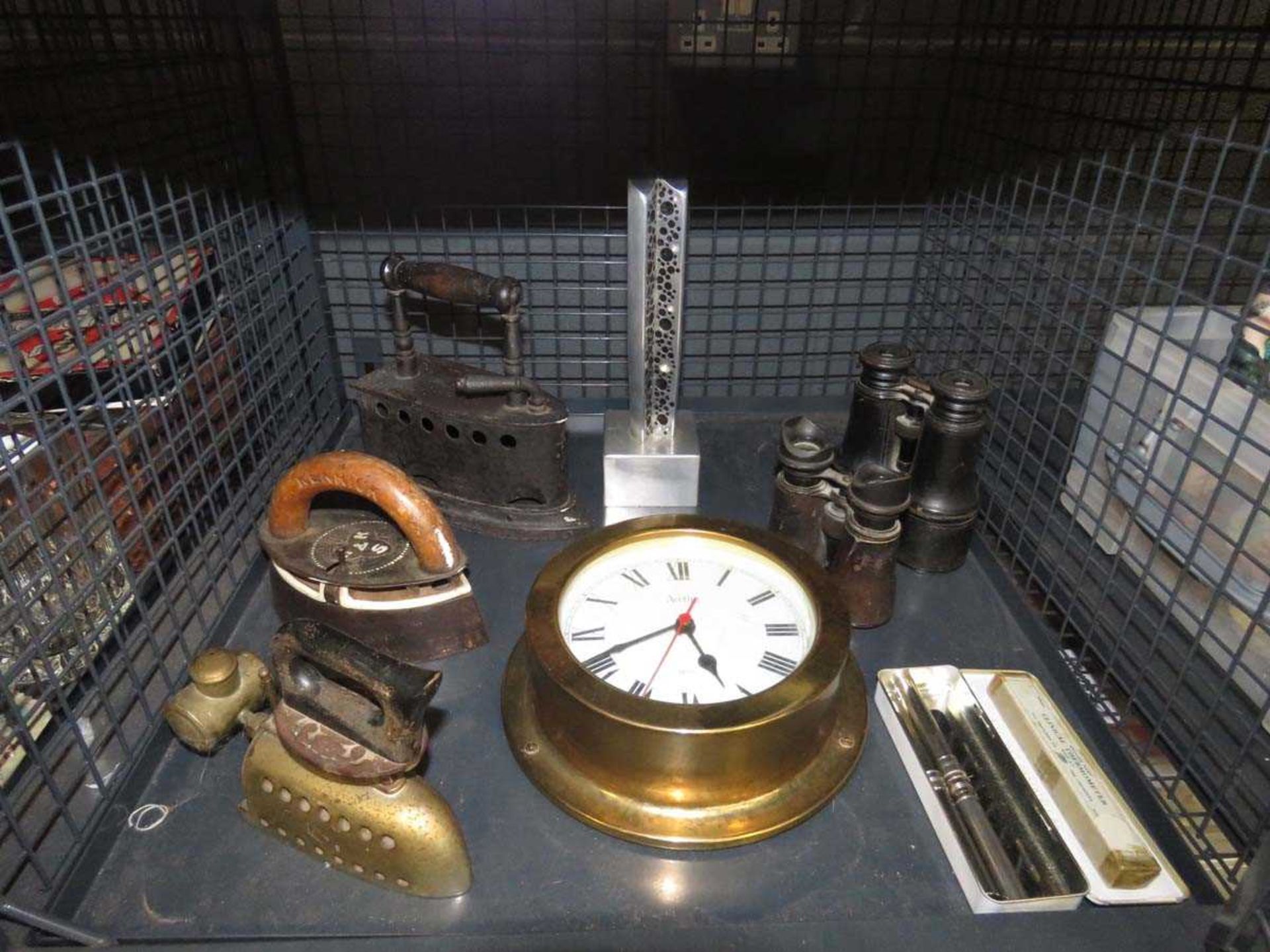 Cage containing flat irons, Acctim quartz clock, binoculars and an aluminium ornament