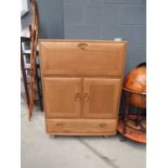 An Ercol Model 469 elm bureau with a fall-front, pair of doors and drawer, on castors, w. 82 cm