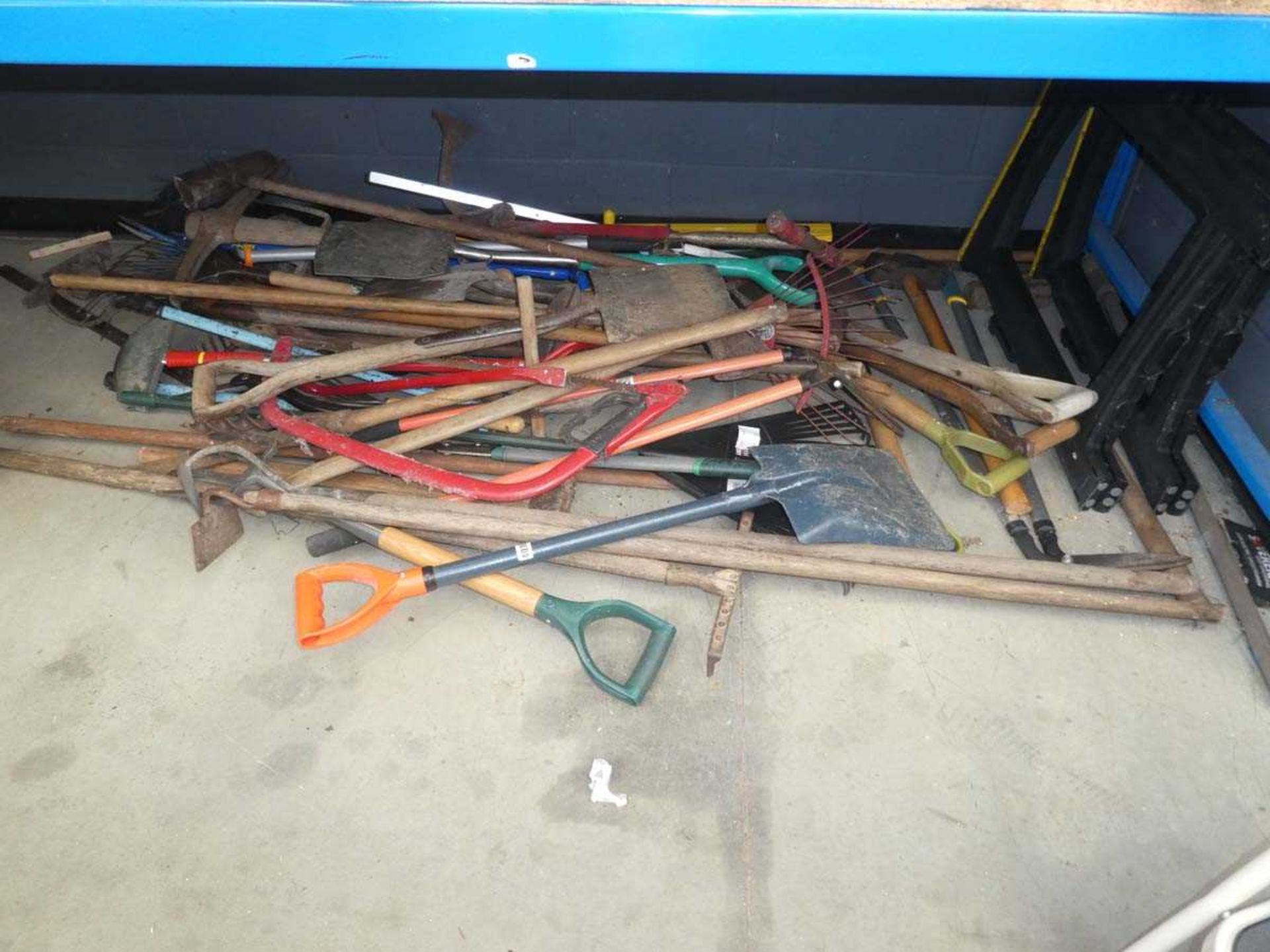 3/4 underbay of garden tools including shovels, forks, saws, loppers, rakes, sawhorses etc.