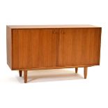 A 1960's teak two-door cabinet with a beech interior and shaped handles, on later tapering legs,