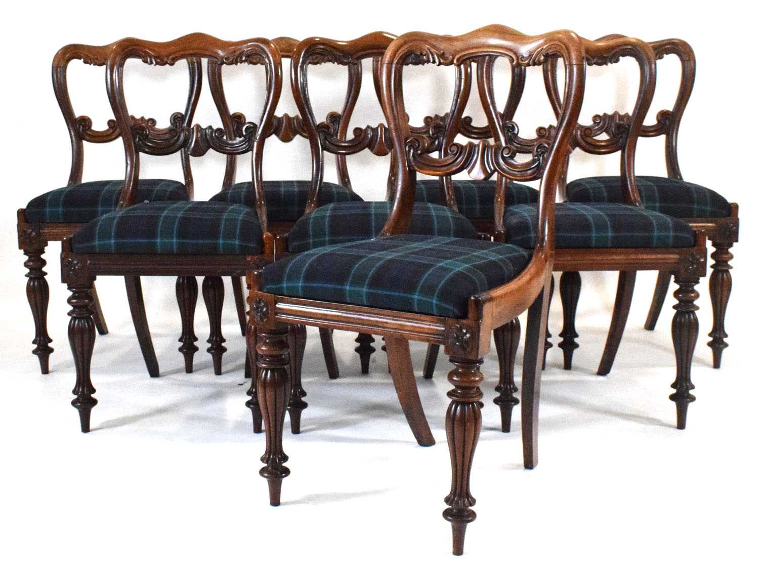 A set of eight Victorian rosewood dining chairs with scrolled balloon backs on reeded baluster