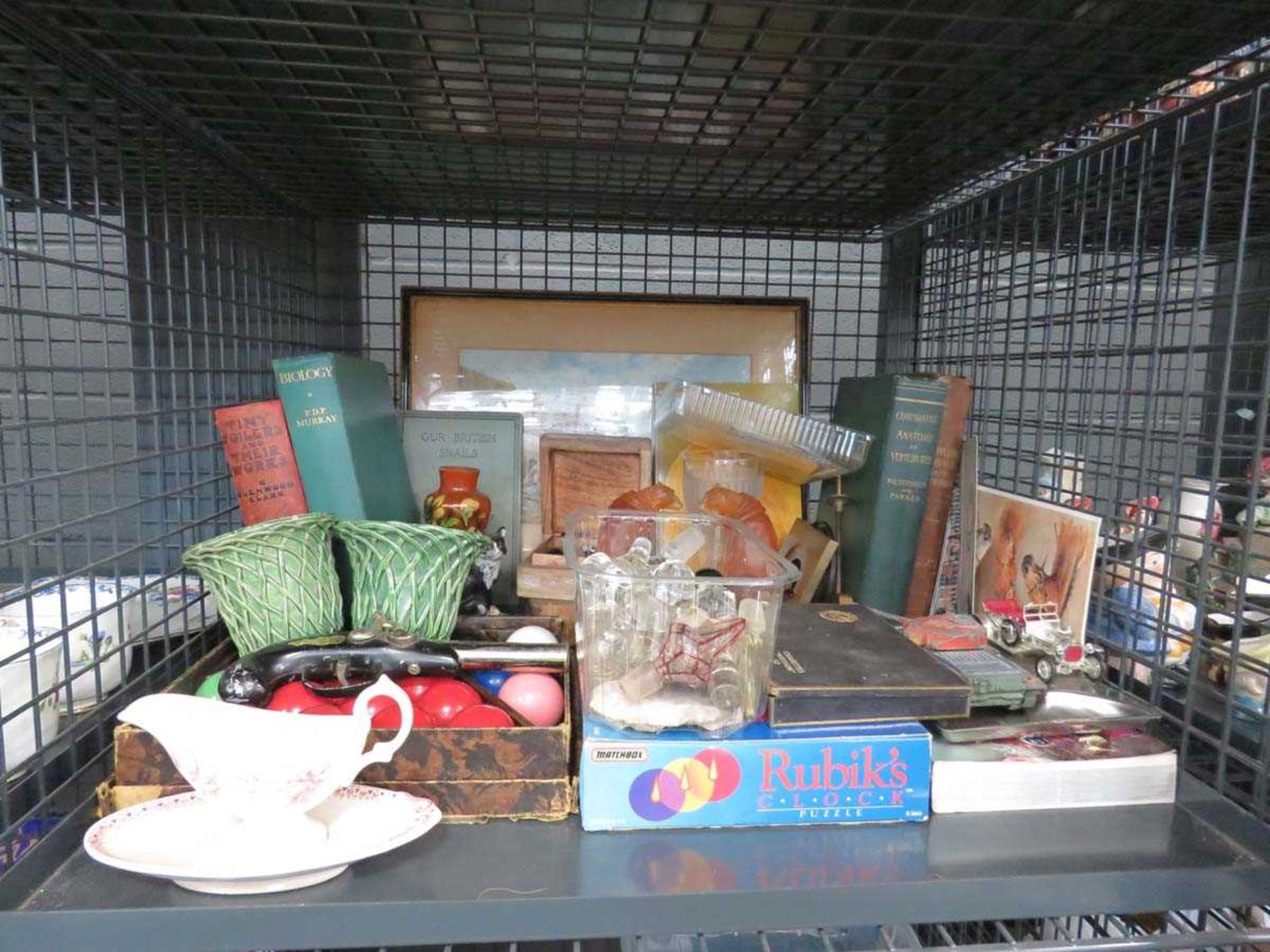 Cage containing reference books, print of a cottage, pool balls, glass stoppers, resin figures and