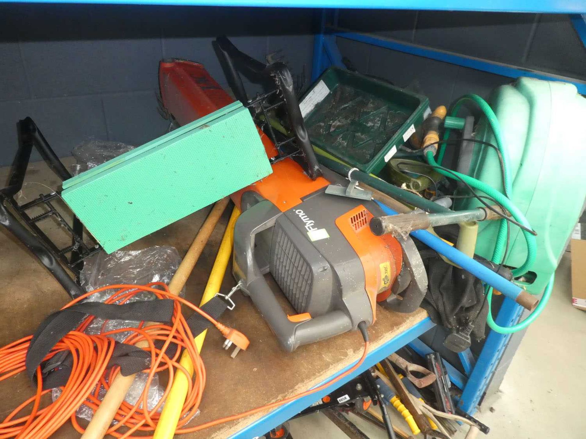 Half a shelf containing hose pipe, Flymo blow vac, kneeling stool and various garden tools