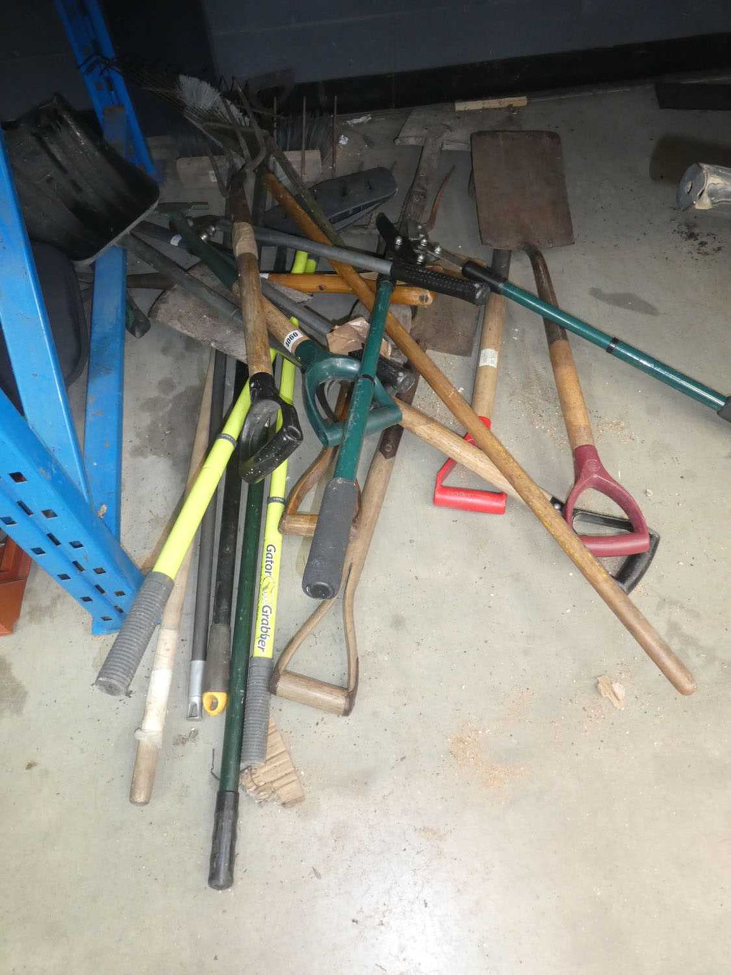 Quarter of a bay of assorted garden tools including brushes, hose, spades, racks etc